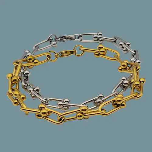 Two chain link bracelets, one gold-toned and one silver-toned, with U-shaped links and spherical studs.
