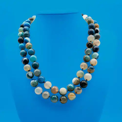 A two-strand necklace made of round, polished natural stone beads in varying shades of blue, green, brown, and cream.